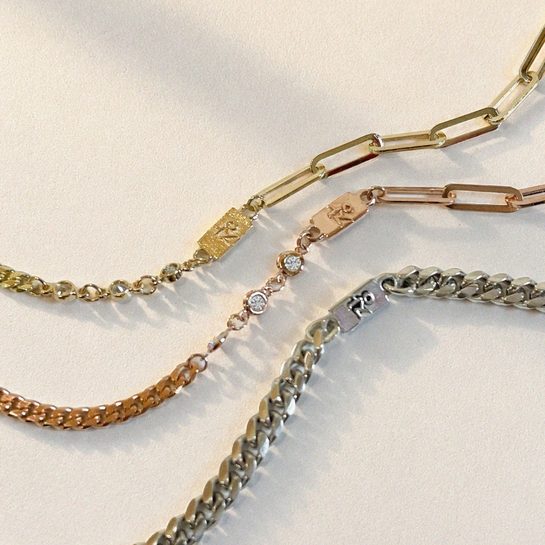 Three custom bracelets arranged on a softly lit white surface. The set includes a yellow gold mixed-link bracelet with a rectangular Korean nameplate, a rose gold bracelet with bezel-set round diamonds and a matching nameplate, and a sterling silver curb chain bracelet. Each bracelet features the raised Korean character "장," symbolizing a shared family connection while reflecting each wearer's individual style.