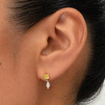 Close-up of an ear wearing a yellow gemstone stud earring with a detachable marquise-cut diamond drop charm.