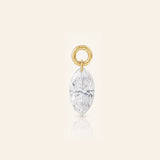 Marquise-cut diamond drop charm suspended from a polished gold loop, photographed with a subtle reflection on a warm ivory background.