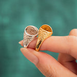 Close-up of silver and yellow gold Reversible Dojang Rings held side by side, highlighting the reversible circular seal faces and ornate floral filigree bands.